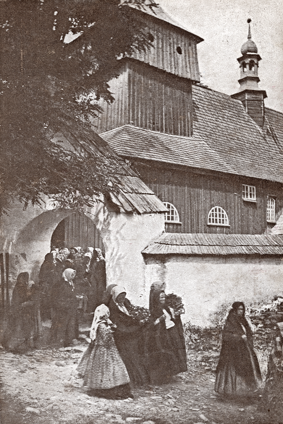 zdjęcie czarnobiałe, kobiety w długich spódnicach i chustach na głowach wychodzą przez bramę kościoła